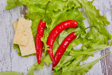Salad, cheese and chile pepper on rustic table