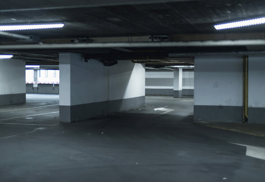 Empty parking garage illuminated by fluorescent lights.
