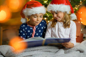 Fototapeta na wymiar Kids reading book by Christmas tree