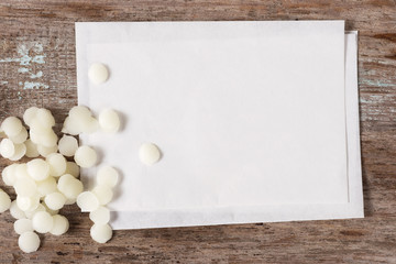 white cosmetic beeswax pellets on blank recipe paper.
