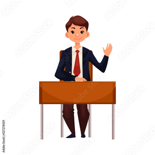 Clever School Boy Sitting At The Desk And Raising Hand To Answer