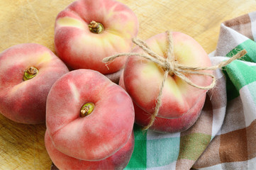 Dough nut peaches also known as Saturn peach with hemp rope  on wooden board.
Benefits of Dough...