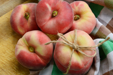 Dough nut peaches also known as Saturn peach with hemp rope  on wooden board.
Benefits of Dough nut peaches. 
