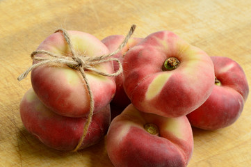 Dough nut peaches also known as Saturn peach with hemp rope  on wooden board.
Benefits of Dough nut peaches.