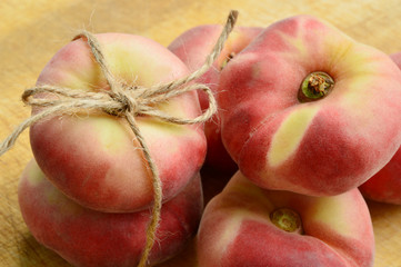 Dough nut peaches also known as Saturn peach with hemp rope  on wooden board.
Benefits of Dough...
