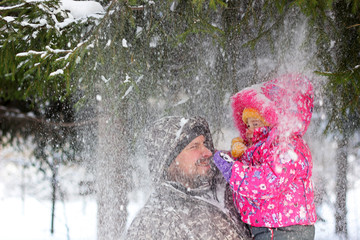 Fototapeta na wymiar Father together with the daughter under falling snow flakes from