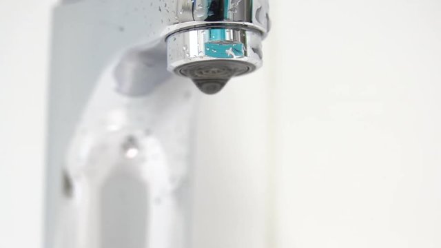 Bathroom sink and faucet with water dripping in close up.