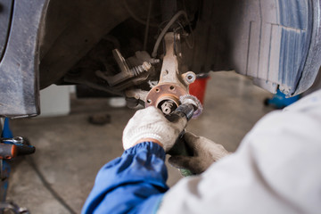 Brand new brake disc on car in a garage. Auto mechanic repairing .