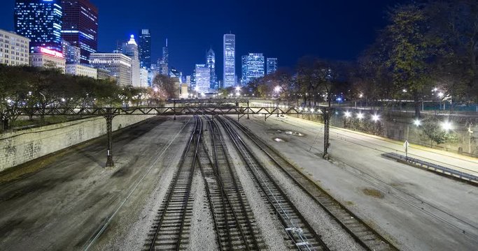 Chicago, Illinois, USA - rails and the Chicago L / Elevated near Millennium Park with illuminated Skyline in the background at night - Timelapse with zoom in