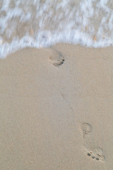 Следы человека на песке, которые смывает морская волна