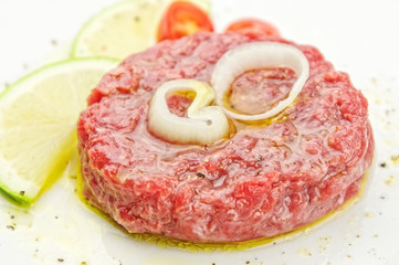 Steak tartare closeup  with lemon slices on white plate