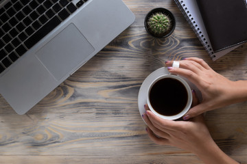 Coffee break. Close-up top view of hands holding cup with coffee