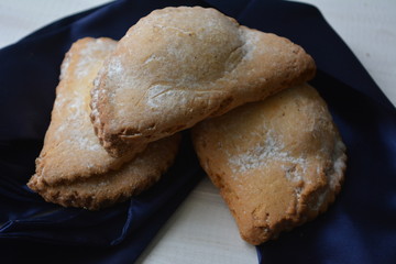 Three delicious biscuits with powdered sugar on a blue satin material, baking