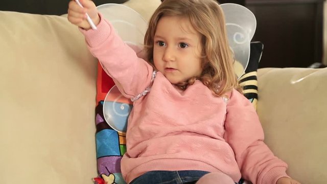 Beautiful little kid with wings, sit and smile on sofa at home interior