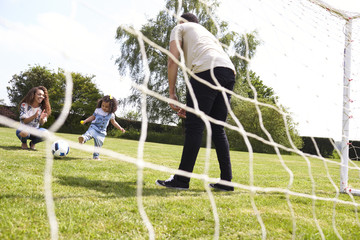 Young girl playing football with her parents, low angle view