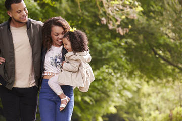 Family of three on a walk, mother holding child, close up