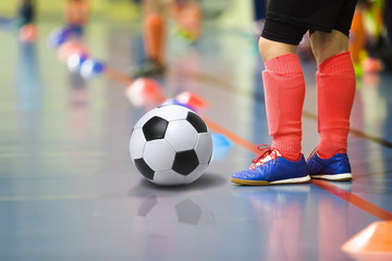 Children training soccer futsal indoor gym. Young boy with soccer ball training indoor football. Little player in light red sports socks