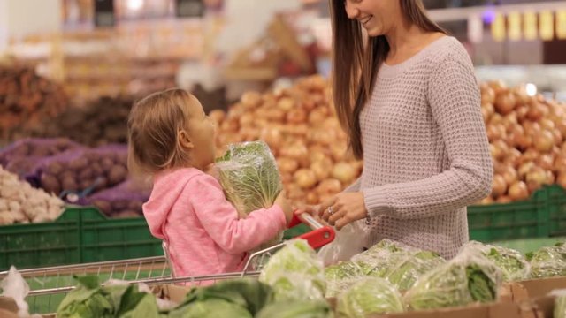 Mother and daughter selecting vegetables while grocery shopping in supermarket