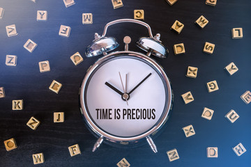 Time is precious - Alarm clock on wooden table with letters - obrazy, fototapety, plakaty