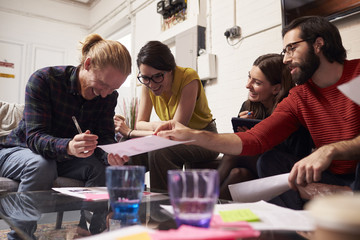 Designers Sitting On Sofa Having Creative Meeting In Office