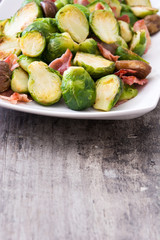 Brussels sprouts with chestnuts and bacon on wooden table
