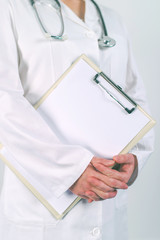 Female doctor in white uniform posing with blank clipboard pad