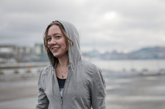 Portrait of young female runner wearing hoody on windy dockside