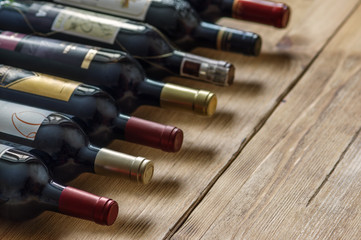 Row of red dry wine bottles on wooden background. Low depth of field. 