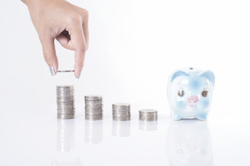 business women hand putting coin on money tower and piggy bank. concept saving finance and investment.