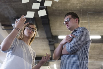 young couple at modern office interior writing notes on stickers