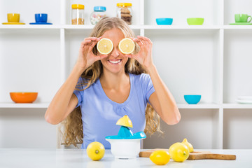 Beautiful girl is covering her eyes with slices of lemon while making lemonade.
