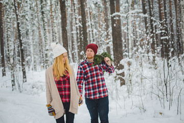 young couple with fir twigs walk in the winter woods