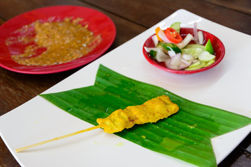 Thai pork satay, grilled pork on white dish with sauce