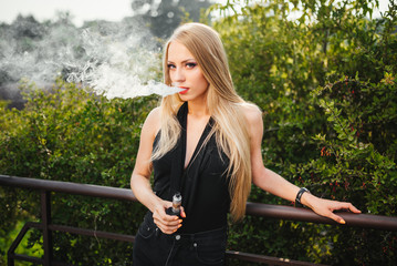 Sexy girl smokes electronic cigarette. The model vaper vaping a vaporizer. Vaping.