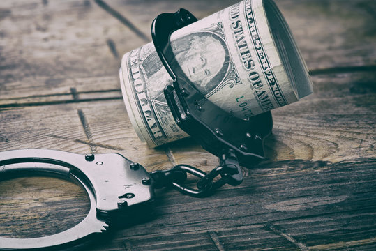 Handcuffs And Money On Wooden Table