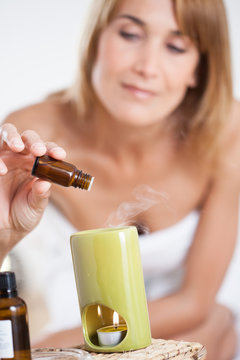 belle femme qui met des gouttes d'huile essentielle dans un diffuseur de parfum