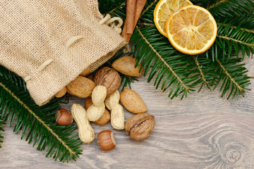 Nüsse mit Jutesack, Tannen, Zimt und Orangenscheiben  auf Holz
