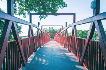 Red bridge with metal structure. Lines in perspective, long pedestrian crossing.