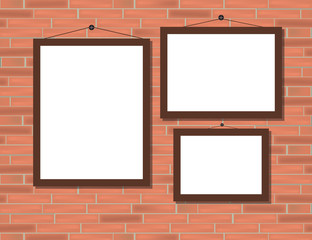 Three empty brown frames on red brick wall.