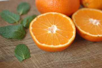 Several mandarin oranges cut in half on a wooden background.