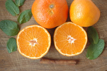 Several mandarin oranges cut in half on a wooden background.