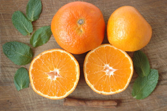 Several mandarin oranges cut in half on a wooden background.
