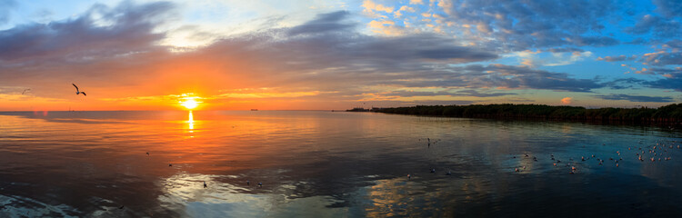 Panorama Tranquil scene cloudy sea sunset with seagulls flying at sunset at Bang Poo Recreational Retreat, Samut Prakan, Thailand. 