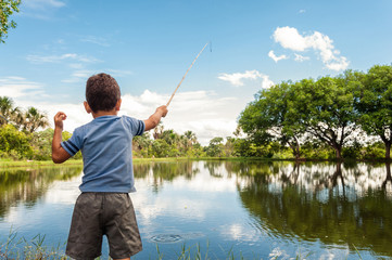 Kid learning how to fish, holding a rod on a lake