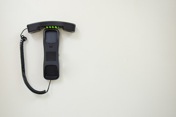 Hang up Retro style black press-button telephone mounted on a white wall.