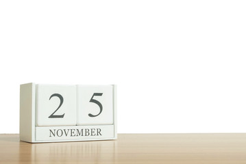 Closeup surface white wooden calendar with black 25 november word on blurred brown wood desk isolated on white background with copy space , selective focus at the calendar