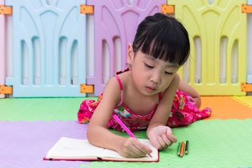 Asian Chinese little girl laying on the floor coloring