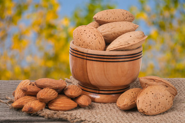 almonds in a bowl on the old wooden board blurred garden background