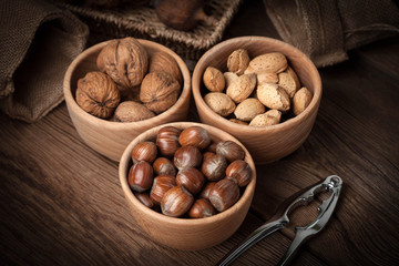 Walnuts, hazelnuts and almonds in-shell in wooden bowl.