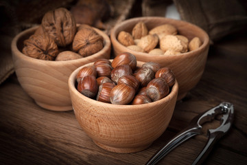 Walnuts, hazelnuts and almonds in-shell in wooden bowl.